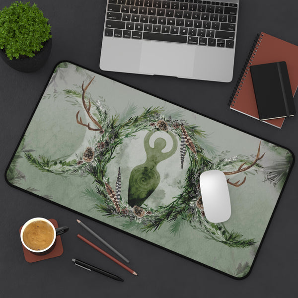a desk with various items, including a laptop, a mouse, a coffee cup, and a plant. The desk also has a decorative mat with a green and white floral design, a keyboard, and some pens and pencils.