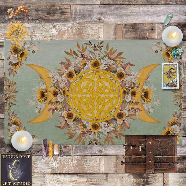 a large, intricate design with a yellow Celtic knot at the center, surrounded by a floral arrangement of sunflowers and other flowers. The design is set against a green background, and there are candles and crystals placed around it. The overall scene appears to be a decorative display or artwork.