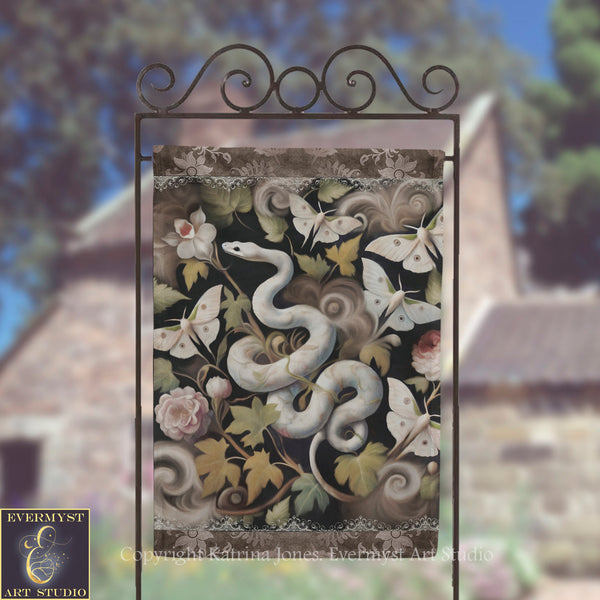 a decorative banner with a snake and butterflies on a metal frame, set against a blurred background of trees and a building.