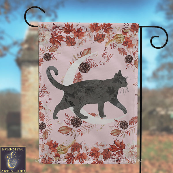 A black cat silhouette is depicted against a pink background with autumn leaves and pine cones.