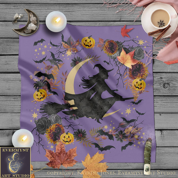 a purple fabric with a witch silhouette and various Halloween-themed elements, including pumpkins, bats, flowers, and leaves, arranged on a wooden surface.