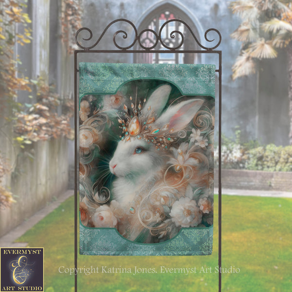 a large, ornate sign with a detailed illustration of a white rabbit wearing a crown and surrounded by flowers. The sign is placed in a garden setting with a stone wall and a building visible in the background.