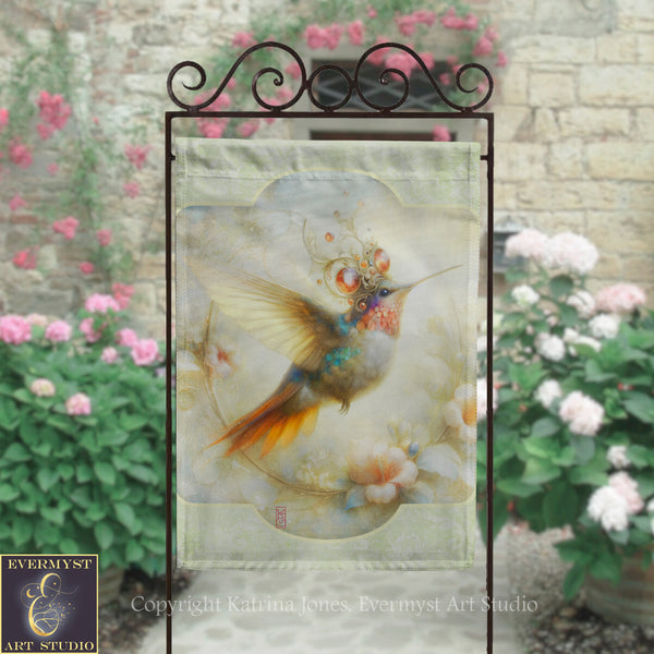 a hanging banner with a colorful hummingbird design, displayed in front of a stone wall with pink flowers.