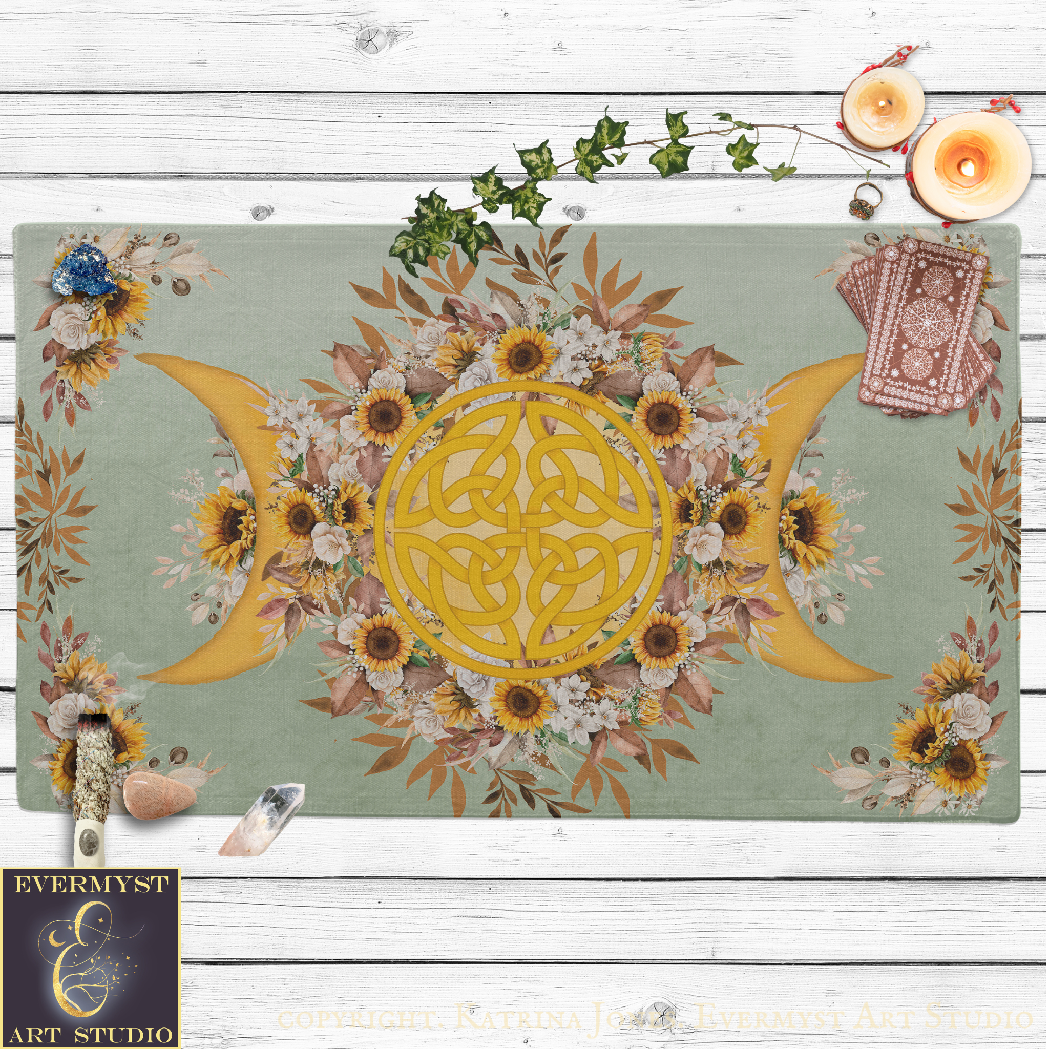 a vibrant and intricate design with a central motif of a crescent moon surrounded by sunflowers and other flowers. The design is set against a light green background, and there are candles and crystals placed around the design, adding to the overall aesthetic.