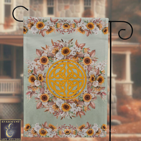 a banner with a floral design and a Celtic knot pattern, hanging on a metal hook.