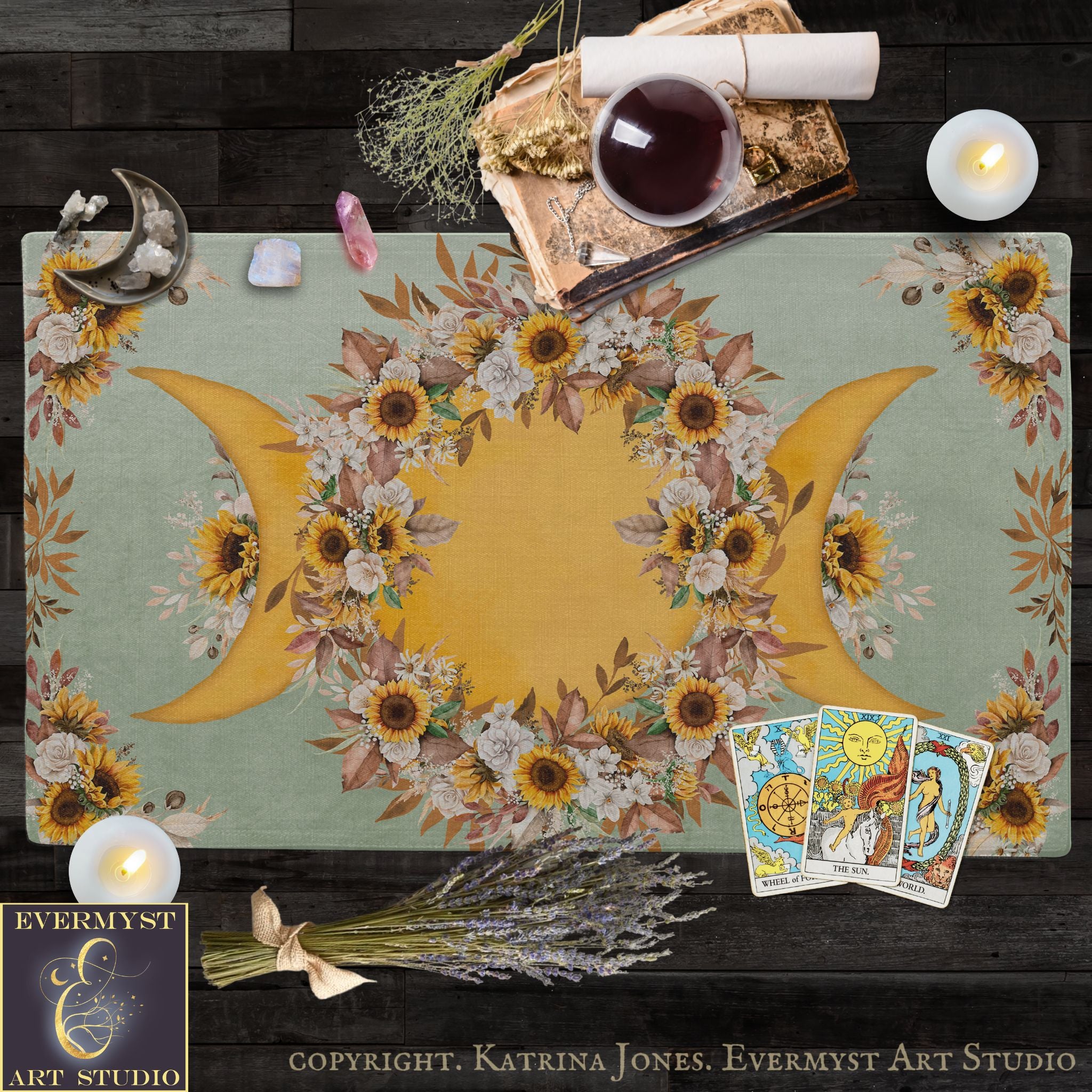 a table with a floral design, candles, and various objects, including a book, crystals, and tarot cards.