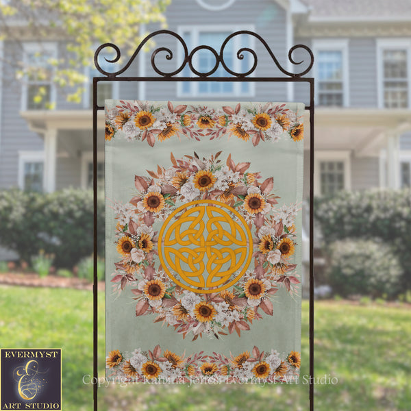 a banner with a floral design and a Celtic knot motif, displayed on a metal stand in front of a house.