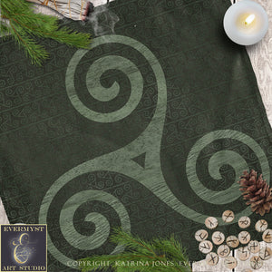 a dark green cloth with a spiral design, pine branches, a lit candle, and some wooden beads or markers.