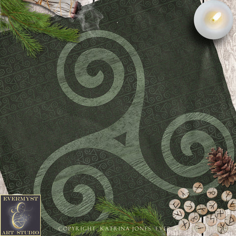 a dark green cloth with a spiral design, pine branches, a lit candle, and some wooden beads or markers.