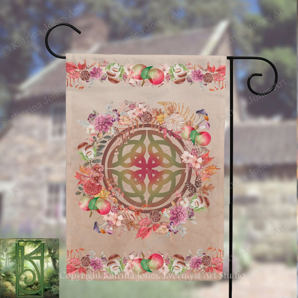 A banner with a circular design featuring a Celtic knot surrounded by various colorful flowers and fruits, such as apples and pears, hanging on a metal hook.