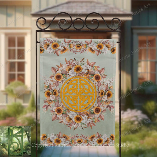 a banner with a floral design and a Celtic knot motif, hanging on a metal stand in front of a house.
