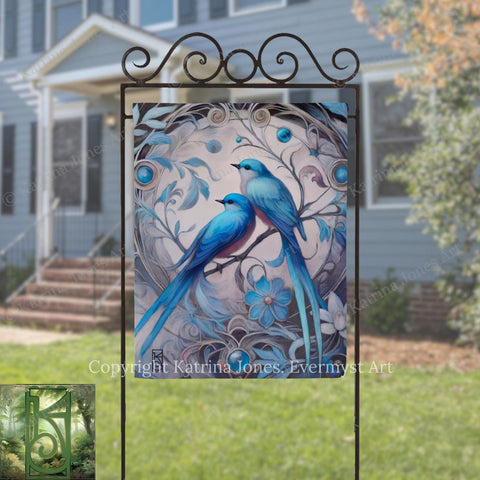 a large, ornate metal sign with a painting of two blue birds perched on a branch, surrounded by intricate floral designs.