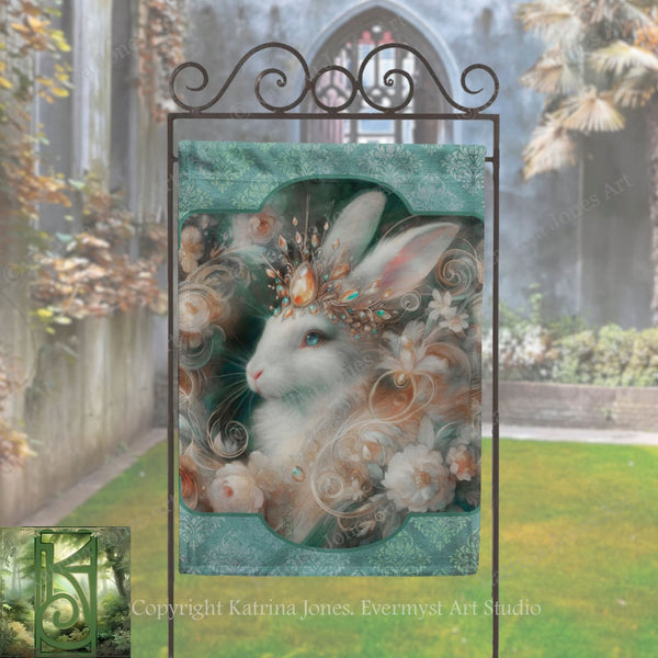 a large, ornate sign with a detailed illustration of a white rabbit wearing a crown and surrounded by flowers. The sign is placed in a garden setting with a stone wall and a building visible in the background.