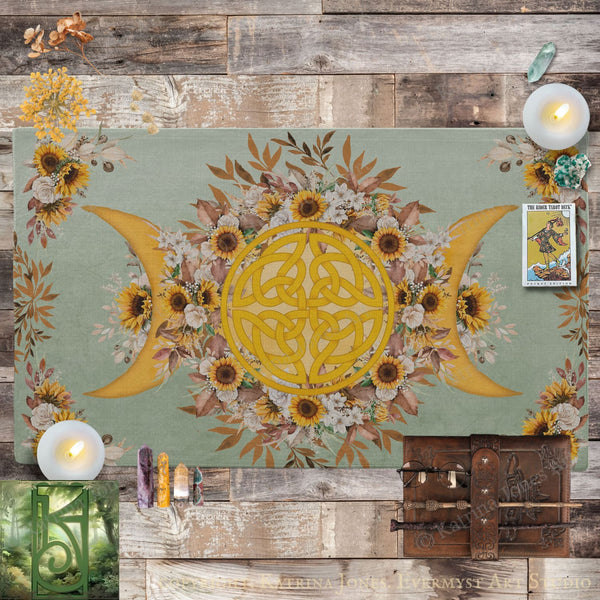 a large, intricate design with a yellow Celtic knot at the center, surrounded by a floral arrangement of sunflowers and other flowers. The design is set against a green background, and there are candles and crystals placed around it. The overall scene appears to be a decorative display or artwork.